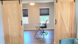 Une pièce dotée d’une grande porte coulissante de style grange, d’un bureau avec une chaise et d’un canapé de couleur turquoise.