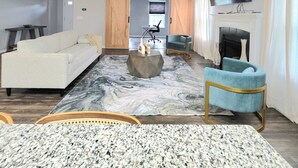 Un salon moderne avec un canapé, une table basse, un téléviseur et une cheminée.