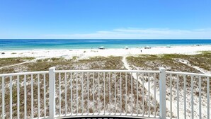 A beach view from a balcony with a white railing, sandy beach, and ocean. - LARGE PRIVATE HOME FOR THE PERFECT VACATION! (Gulf Shores)