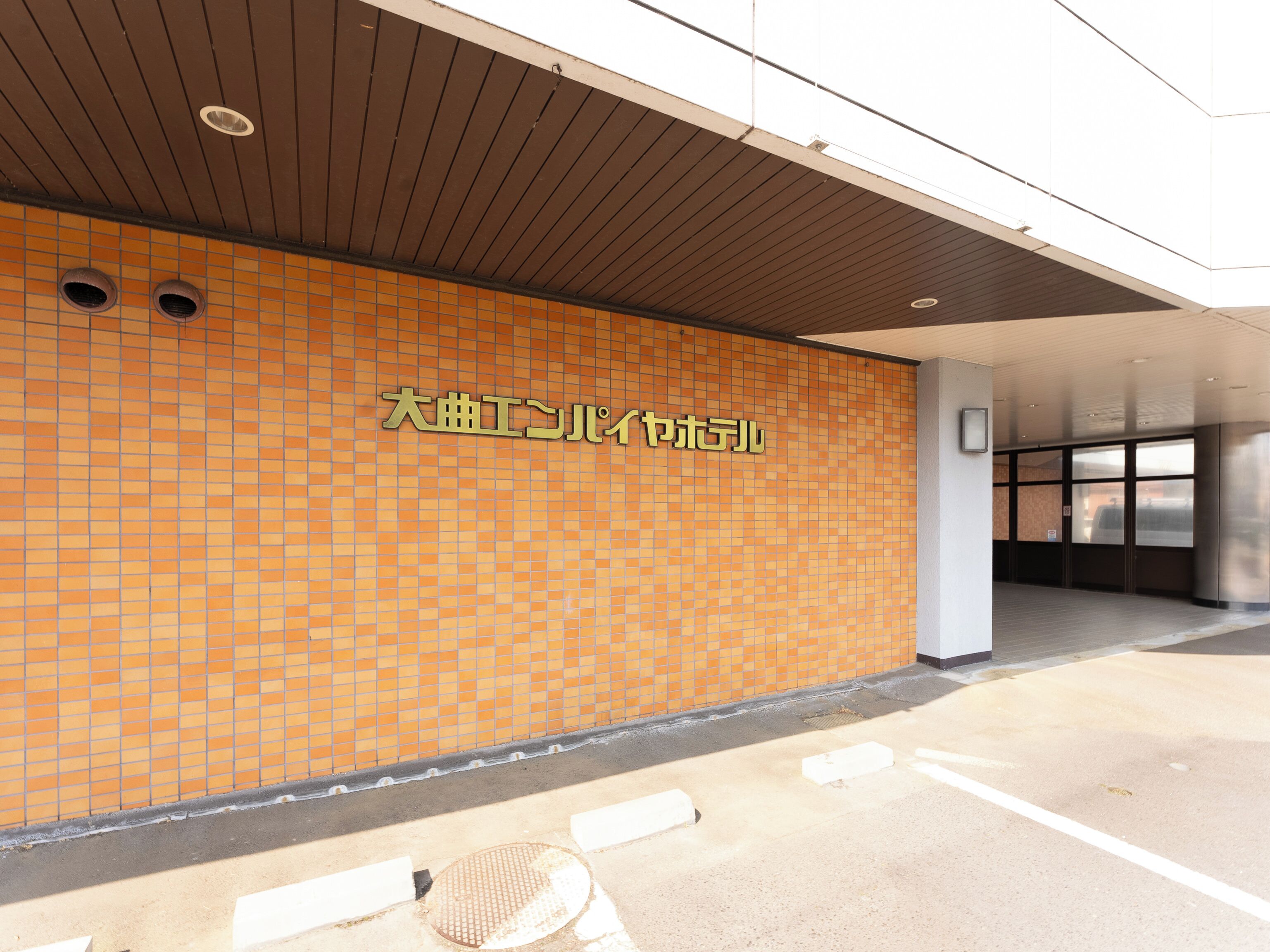 A tiled wall with a sign in a foreign language, a metal door frame, and a concrete floor.