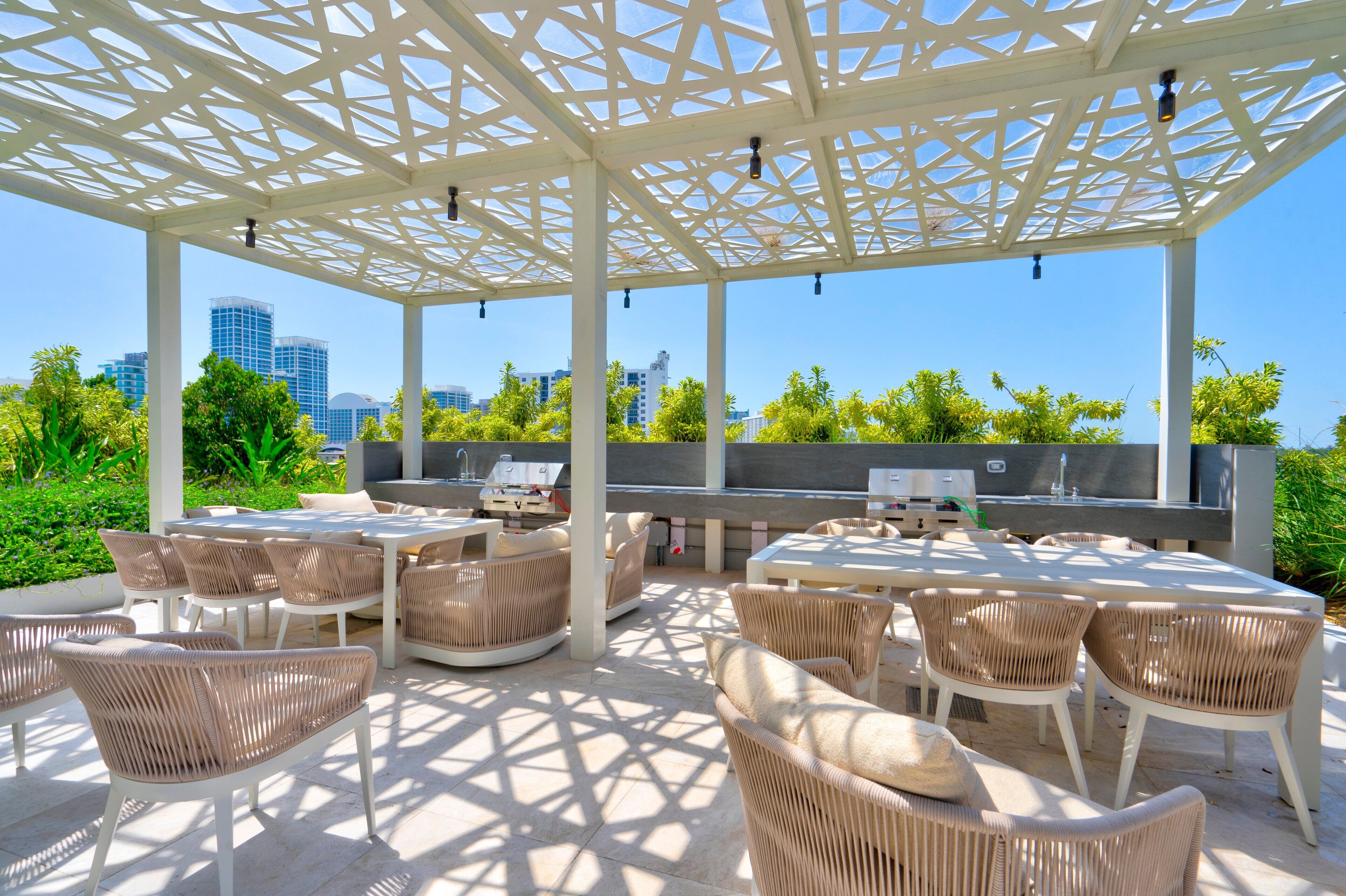 An outdoor patio with wicker furniture, a grill, and a city view.
