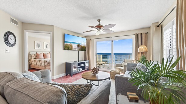 A spacious living room with a large window, a ceiling fan, and a view of the ocean. - Direct oceanfront corner 2/2 with stunning views, huge balcony, heated pool, and garage parking (Ormond Beach)