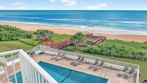 A pool area with lounge chairs and a view of the beach and ocean. - Direct oceanfront corner 2/2 with stunning views, huge balcony, heated pool, and garage parking (Ormond Beach)