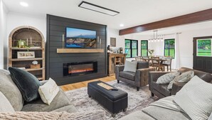 Una sala de estar moderna con chimenea, asientos cómodos y un comedor.
