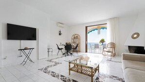 A modern living room with a flat-screen TV, a dining area with chairs and a table, and a sofa. - Case Marcia Mia - 2 adjacent seafront houses (San Montano)