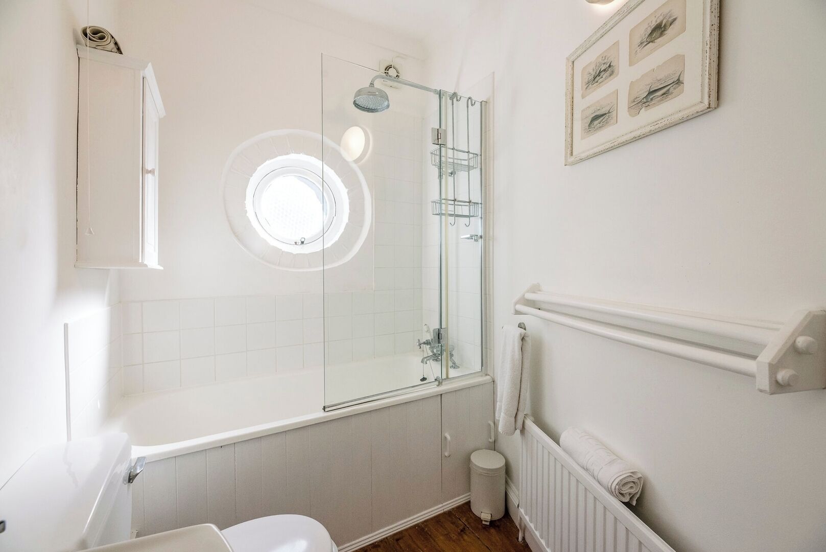 Une salle de bain avec une douche à parois de verre, des toilettes, un lavabo et un radiateur.