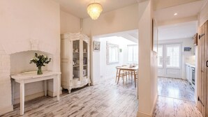 A spacious room with a white fireplace, a dining area with a table and chairs, and a kitchen area with cabinets and a stove.