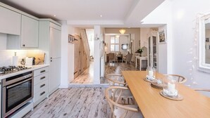 A modern kitchen with white cabinets, a wooden dining table, and a view into the dining area.