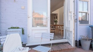 A small, white house with a sliding glass door leading to a dining area with a table and chairs.