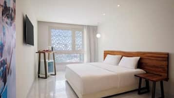 Quarto de hotel com cama, mesa de cabeceira, escrivaninha e janela com vista.