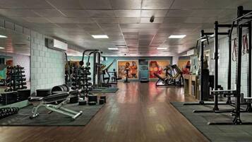 A gym with weightlifting equipment, treadmills, and a mirrored wall.