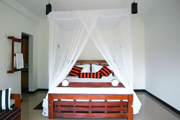 A bed with a wooden frame and white bedding, a white canopy, and striped pillows.