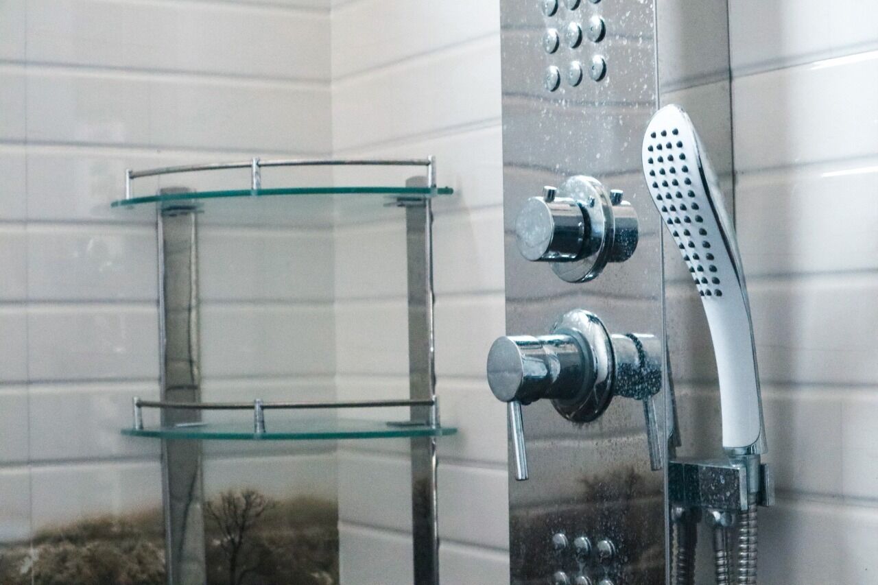 Un baño con cabina de ducha de vidrio, ducha de mano y grifo empotrado.