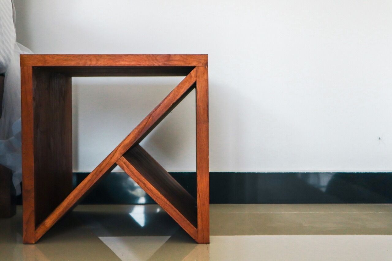 Una mesita de noche de madera con un diseño geométrico sencillo.