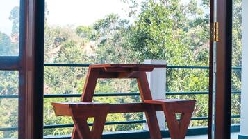 Una sedia di legno con struttura metallica su un balcone affacciato su un pendio boscoso.