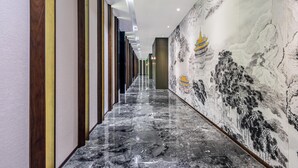 Un pasillo con piso de mármol, paneles de madera verticales y un mural de una edificación tradicional.
