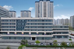 A modern hotel with a prominent entrance, multiple floors, and a parking area in front. - Madison Hotel Yangzhou East High-speed Railway Sta (Yangzhou)