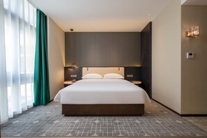 A modern hotel room with a large bed, a nightstand, a lamp, and a view of the city through the window. - Madison Hotel Yangzhou East High-speed Railway Sta (Yangzhou)