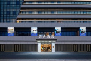 Een hotel met een moderne gevel, meerdere verdiepingen en verlichte signage.