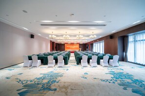 A conference room with rows of tables and chairs, a stage with a banner, and large windows with curtains. - Madison Hotel Yangzhou East High-speed Railway Sta (Yangzhou)