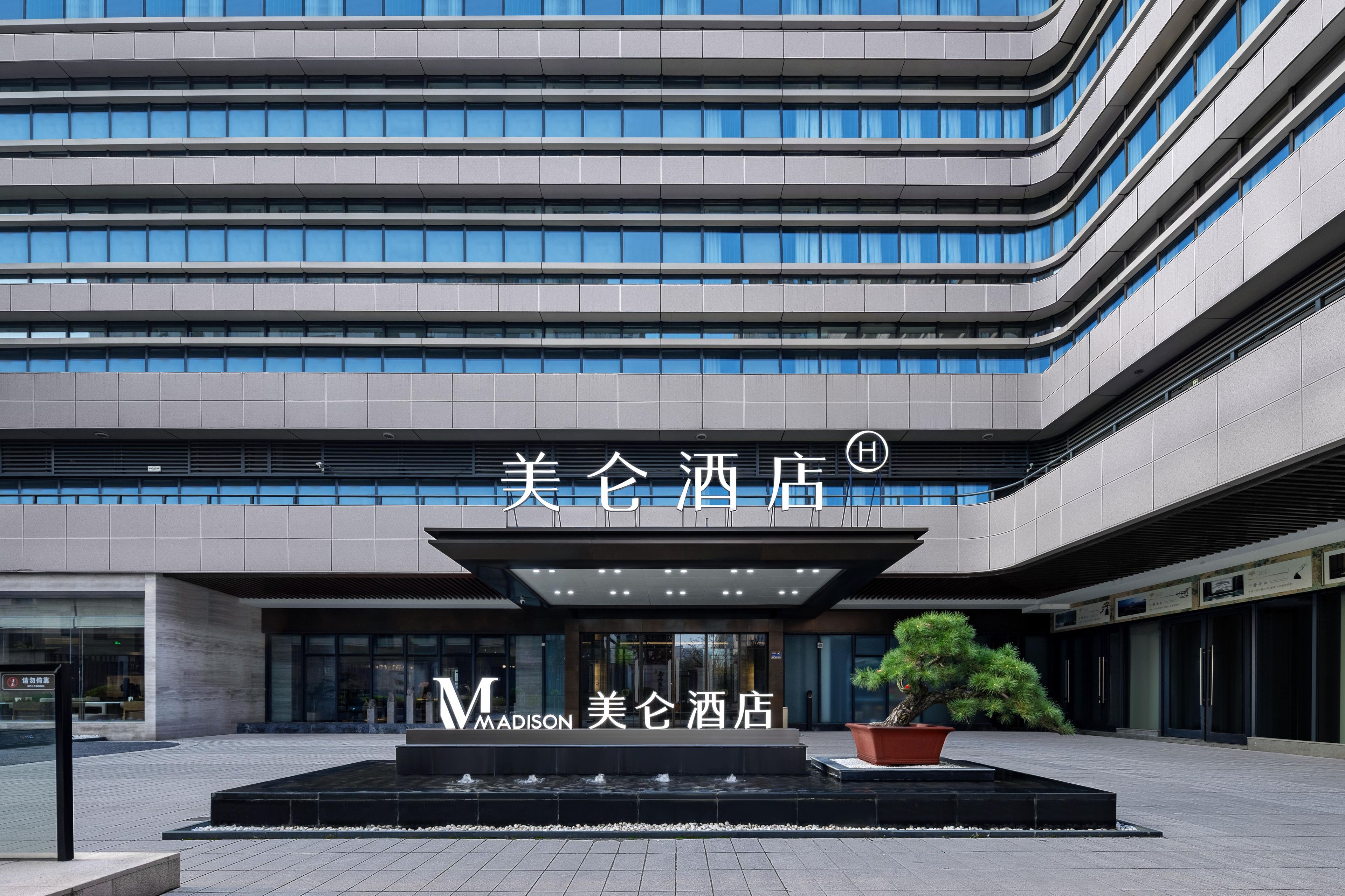 Entrada moderna de un hotel con un cartel grande que dice "Madison Hotel".