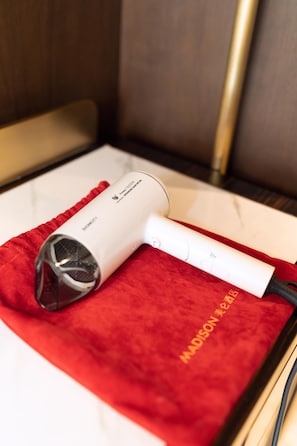 A hair dryer on a red cloth with a book and a cord. - Madison Hotel Yangzhou East High-speed Railway Sta (Yangzhou)