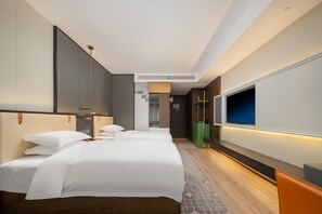 Une chambre d’hôtel moderne avec un grand lit, un téléviseur fixé au mur et un plancher en bois.
