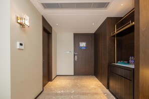 A hallway with a wooden door, a wall-mounted light fixture, and a thermostat. - Madison Hotel Yangzhou East High-speed Railway Sta (Yangzhou)