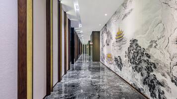 A hallway with a marble floor, vertical wooden panels, and a mural of a traditional building.