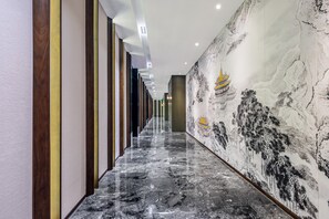 A hallway with a marble floor, vertical wooden panels, and a mural of a traditional building. - Madison Hotel Yangzhou East High-speed Railway Sta (Yangzhou)