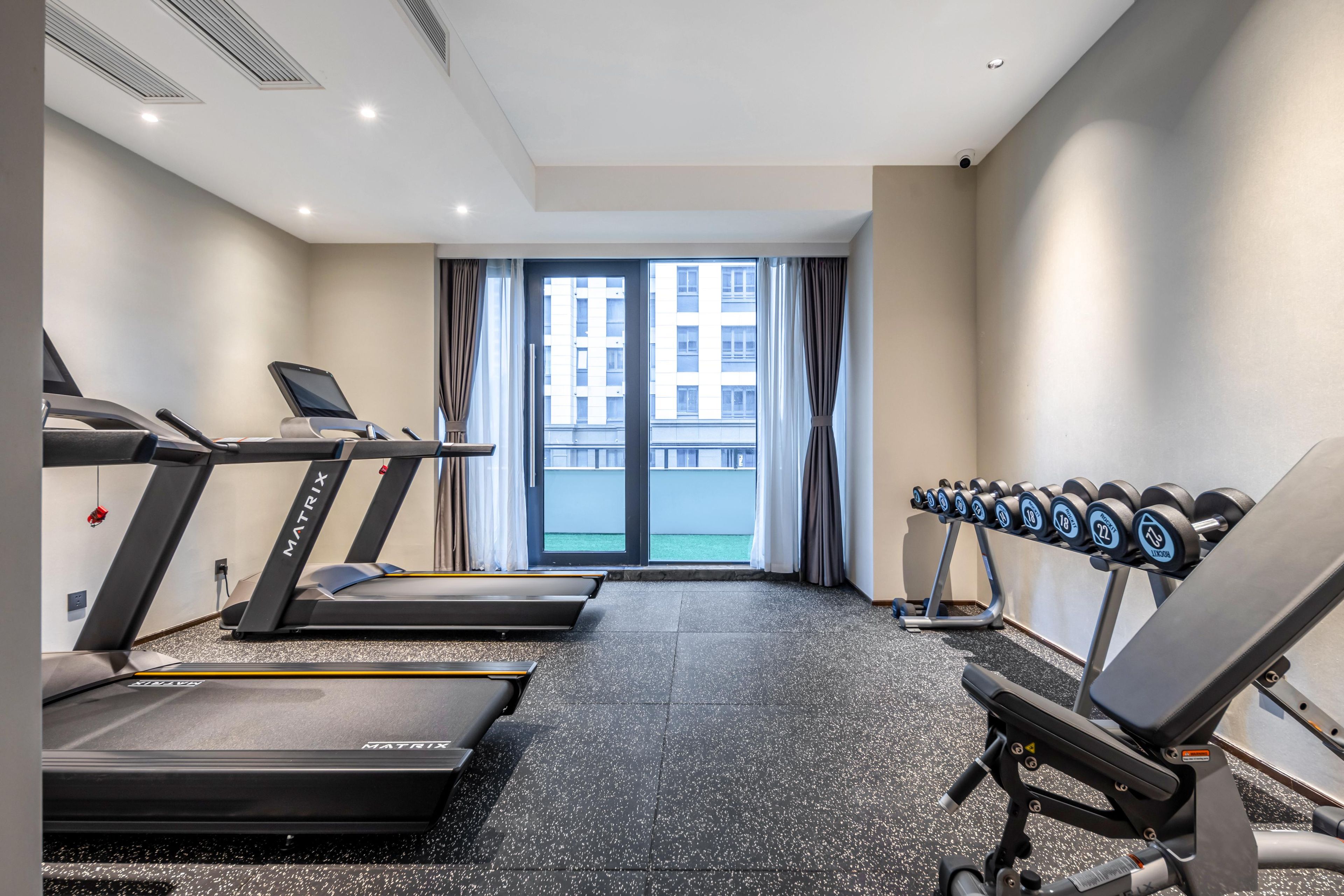 A gym with treadmills, a bench press, and dumbbells.