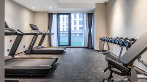 Une salle de sport équipée de tapis de course, d’un banc de développé couché et d’haltères.