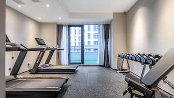 A gym with treadmills, a bench press, and dumbbells.