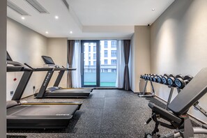Un gimnasio con cintas de correr, una prensa de banca y mancuernas.