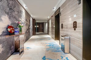 Un ingresso moderno con pavimento in marmo, una reception con un vaso di fiori e un quadro tradizionale appeso al muro.