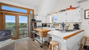 A modern kitchen with white cabinets, a large island, and a view of the outdoors.