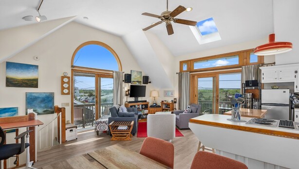 A spacious living area with a high ceiling, a large window, and a kitchen with modern appliances.
