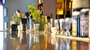 A bar area with a glass display case containing various bottles and a glass vase with greenery. - Hotel Morione & Spa Center (Istanbul)
