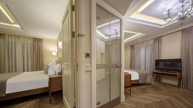 A hotel room with two beds, a TV, a sliding glass door, and a chandelier. - Hotel Morione & Spa Center (Istanbul)