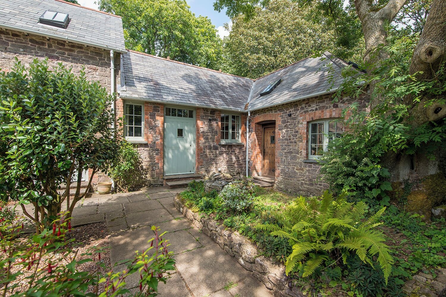 Une maison en pierre avec un toit en pente, une porte d’entrée et un petit porche.