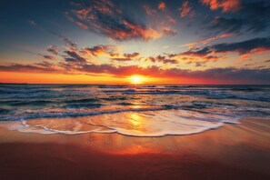 A beach at sunset with waves gently lapping the shore.