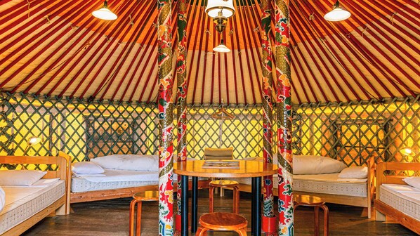 A traditional yurt interior with a central table, cushioned seating, and a hanging light fixture. - Naoshima Tsutsujiso Lodge (Naoshima)