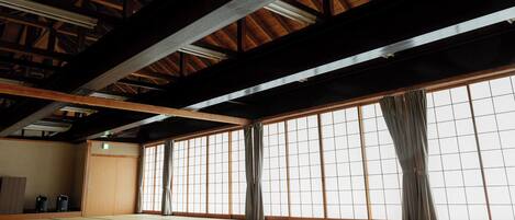 A traditional Japanese room with tatami flooring, sliding shoji doors, and a wooden ceiling structure.