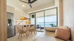 A modern kitchen with a built-in refrigerator, a dining area with a table and chairs, and a balcony with a view of the sea. - Panoramic Oceanview Loft Near Beach & Airport (Cartagena de Indias)