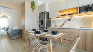 A modern kitchen with a built-in refrigerator, a dining area with two chairs and a table, and a small seating area with a sofa and a plant. - Panoramic Oceanview Loft Near Beach & Airport (Cartagena de Indias)