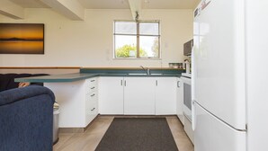 A modern kitchen with white cabinets, a black countertop, and a refrigerator.