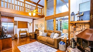 A spacious living room with a high ceiling, wooden beams, a fireplace, and a cozy seating area.