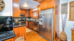 A modern kitchen with wooden cabinets, stainless steel appliances, and a large refrigerator.