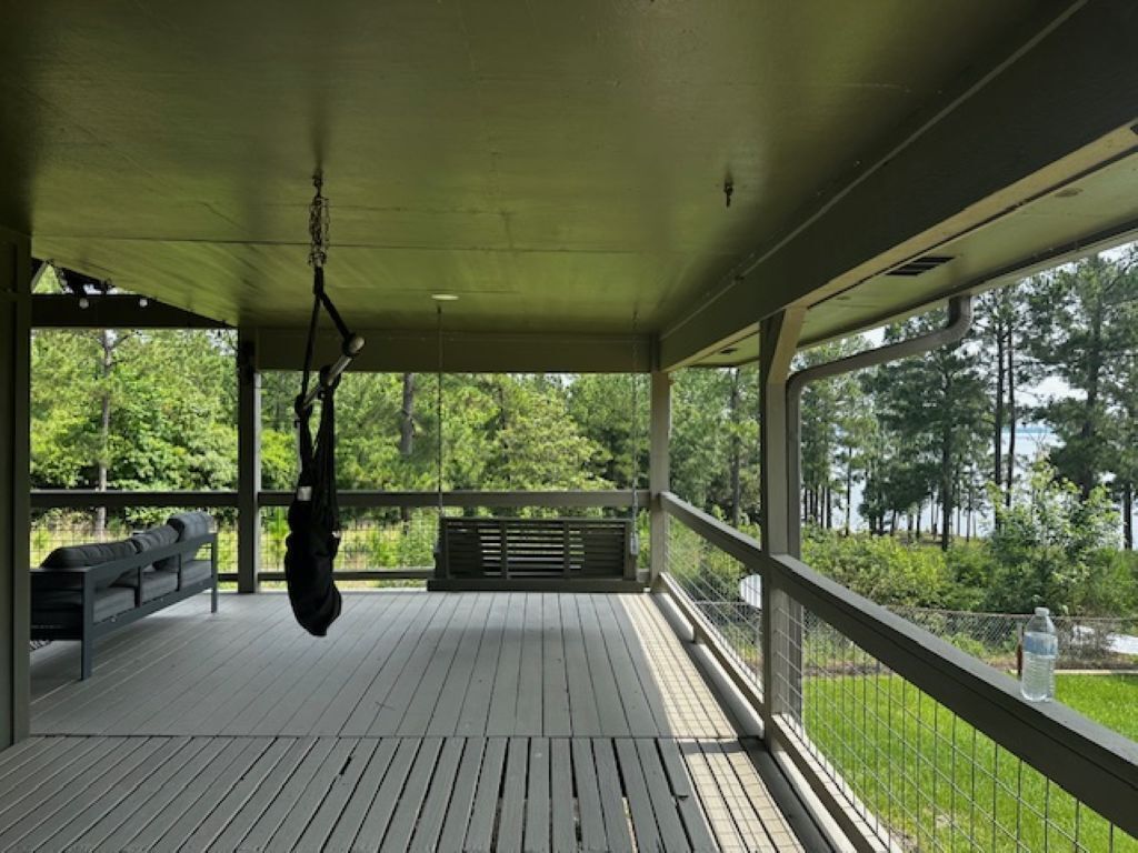 A covered outdoor area with a bench, a hanging bag, and a view of greenery.