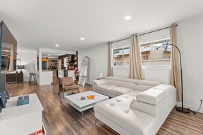 A modern living room with a sofa, coffee table, and a view of the kitchen.